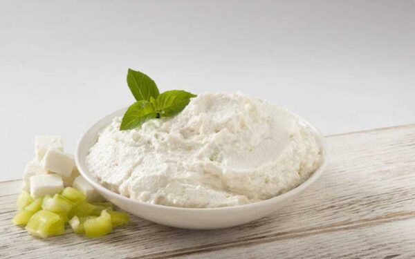 Close-up of bowl with Greek ‘Ktipiti’ a cheese-based spread and fresh green herbs on top