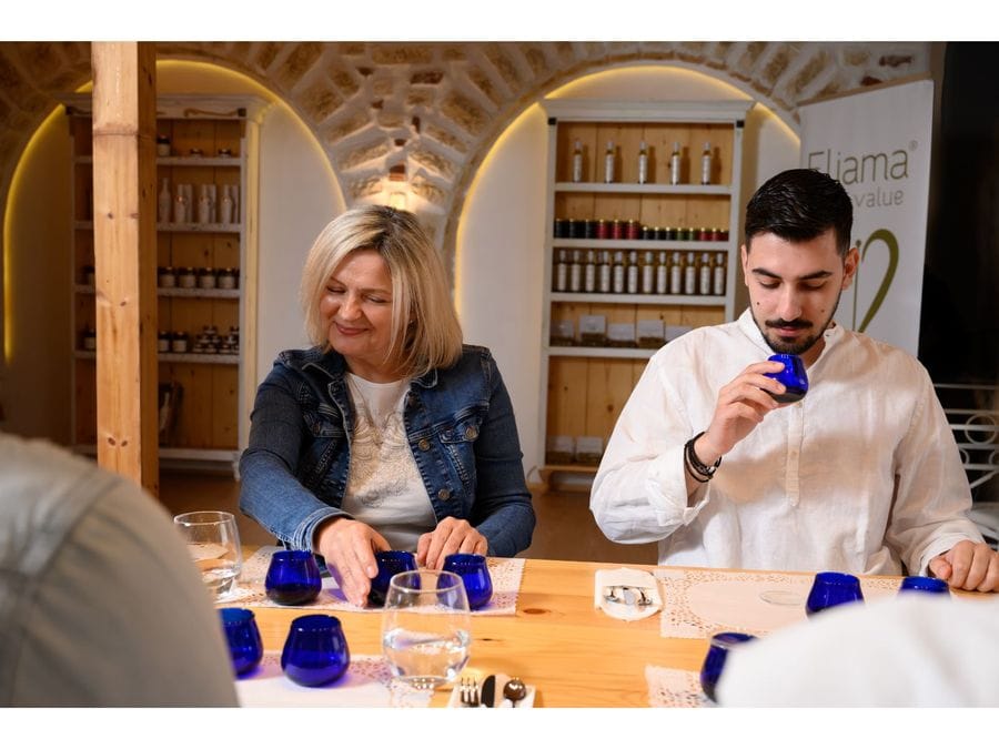 Two engrossed individuals at a table, captivated by the olive oil tasting. Three blue glasses stand before them, reflecting their deep interest and intrigue in the flavors they explore.