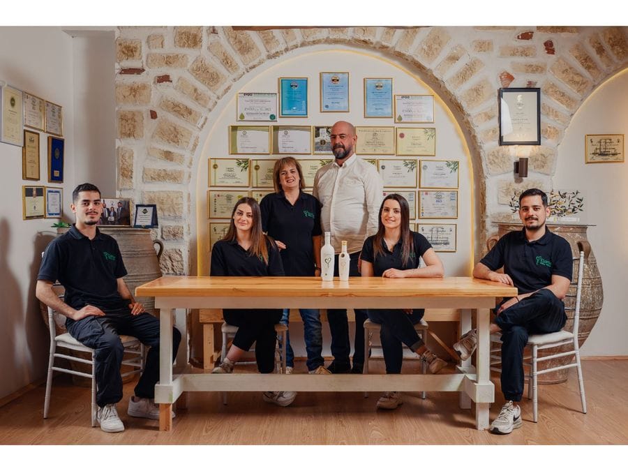 Six Elli's Farm members gathered around a table. Two olive oils take center stage. A snapshot of teamwork and dedication to the craft of olive oil production.