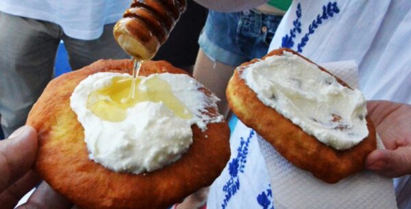 Close-up of two Greek ‘Ladopita’ fried pies with fresh cream cheese and oil on top