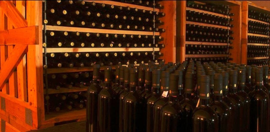 wine bottles in horizontal position and in the storage lockers and on the table at Lafkiotis Winery cellar