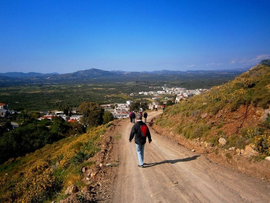 A group of people walks together on a downward road, their steps synchronized. Unified in purpose, they journey with confidence, eager to embrace the adventures awaiting them below.