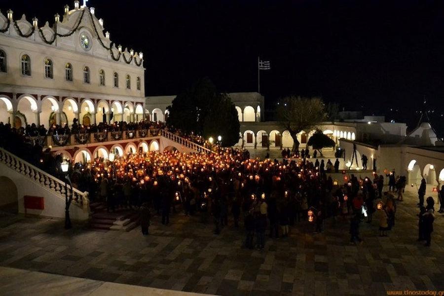 People front the church of Tinos town by night with lanterns
