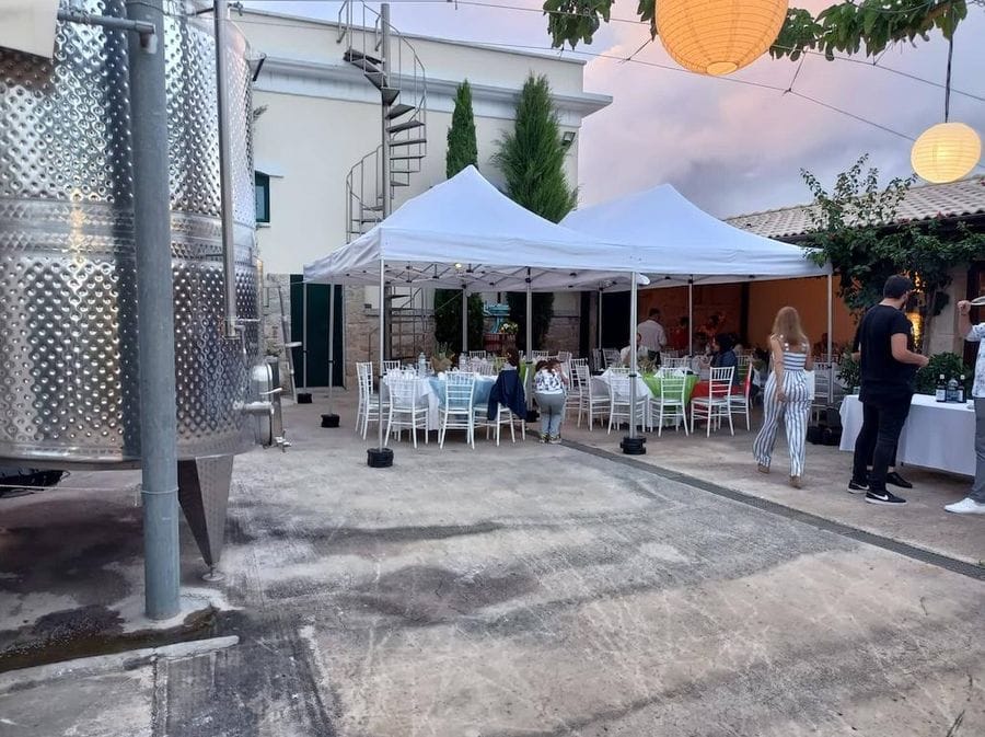 People sitting outside at restaurant Gikas winery and an aluminum wine storage tanks on the left