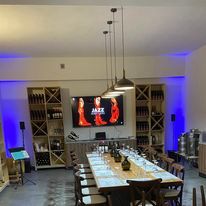 Kappa Winery's restaurant with television, bottles of wine and a table set for wine tasting