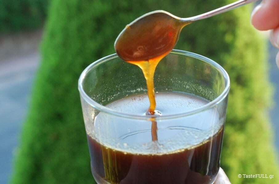 Close-up of glass with Greek ‘Frangosikomelo’ is a natural sweetener and a sweet spoon on top