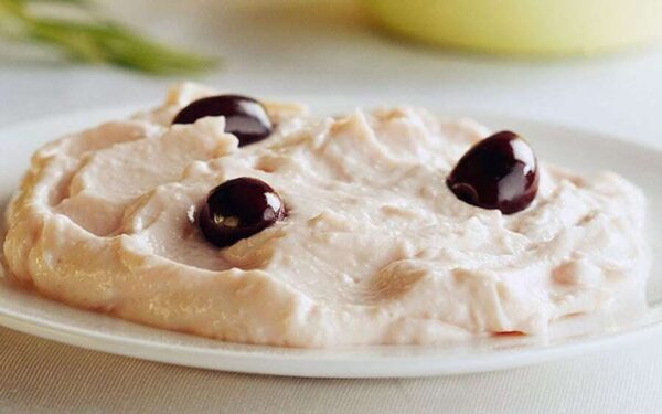 Close-up of plate with white Greek ‘Taramas’ means salad of fish roe with smooth texture and black olives on top|