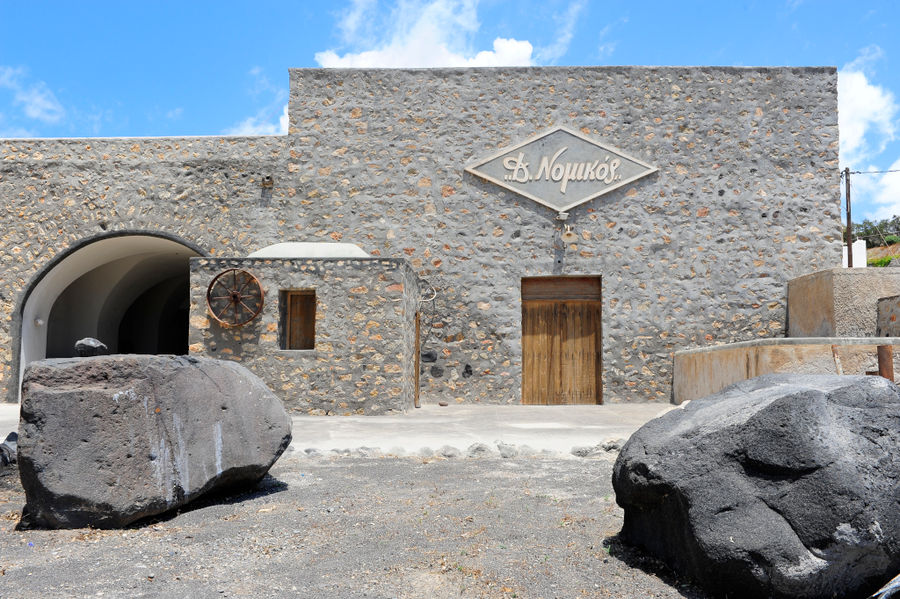 'Tomato Industrial Museum' building that says 'D. Nomikos' in upper part of the wall and huge rocks in front