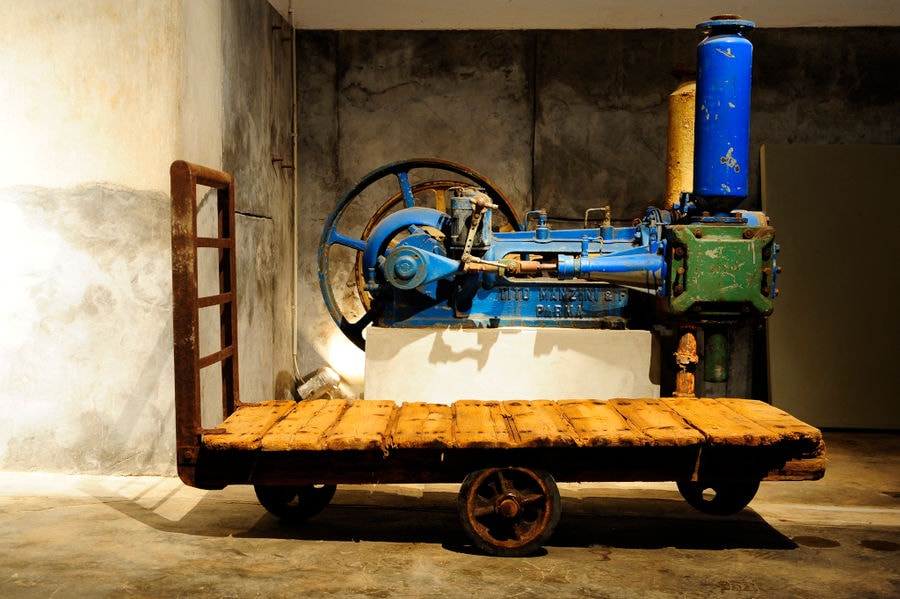 wooden trolley and old blue tomato paste processing machine behind it at 'Tomato Industrial Museum'