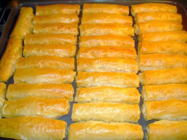 Close-up of rows of rolls of Greek ‘Tzevremedes’ are made of filo filled with fresh cheese