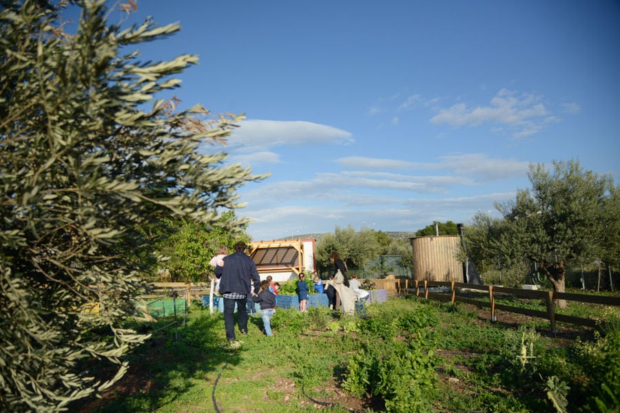 man with childs walking in 'The Orchard in Vari' vegetables garden