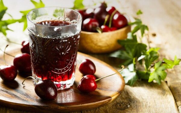 Close-up of glass with Greek ‘Vissinada’ means sour cherry juice and fresh heights in the background