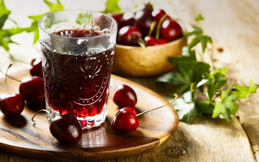 Close-up of glass with Greek ‘Vissinada’ means sour cherry juice and fresh heights in the background