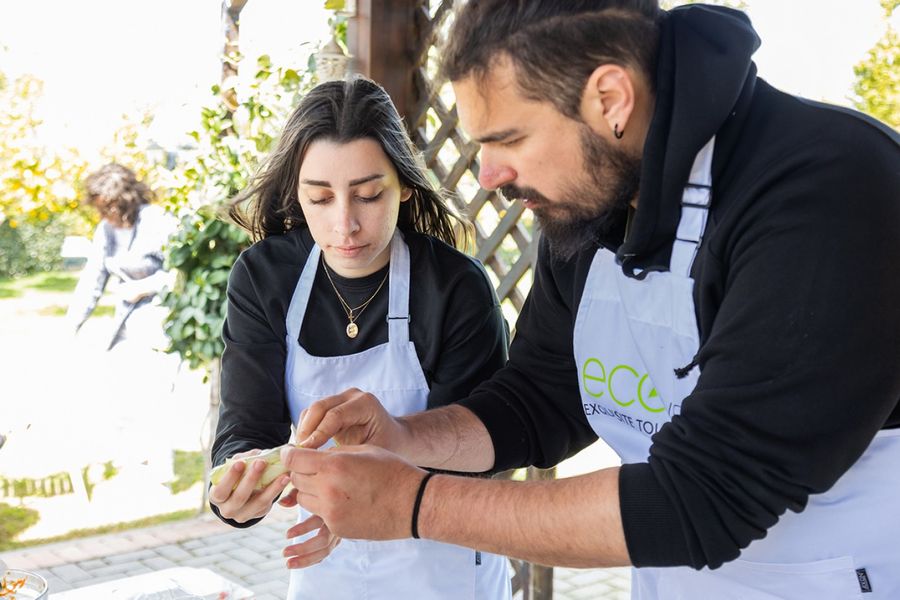 Two people collaborate in filling a small piece of dough, their hands skillfully working together to encase the filling, creating a culinary treasure that promises a burst of flavors and a delightful bite.