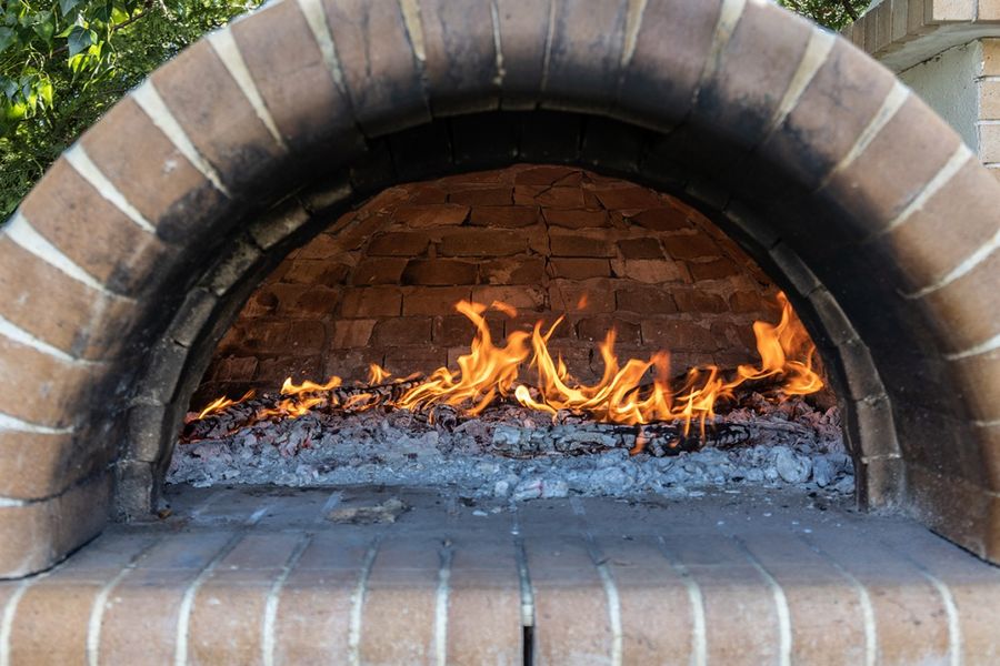 A captivating wood oven stands proud, its rustic charm emanating from the crackling fire within, ready to transform raw ingredients into culinary delights with its radiant heat and timeless appeal.