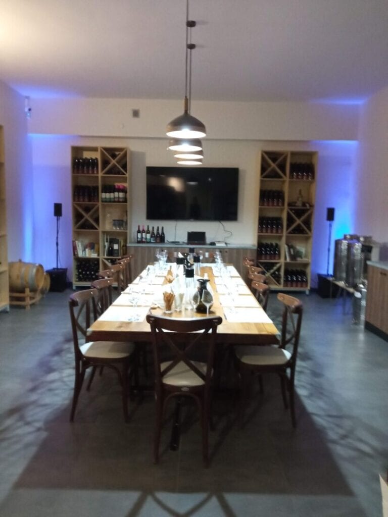 Kappa Winery's restaurant with television, bottles of wine and a table set for wine tasting