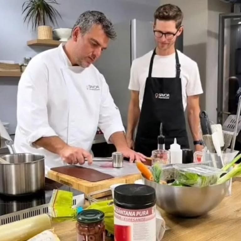 a chef is cooking to his kitchen and a boy with glasses looks at him smiling at Savor Nafplio