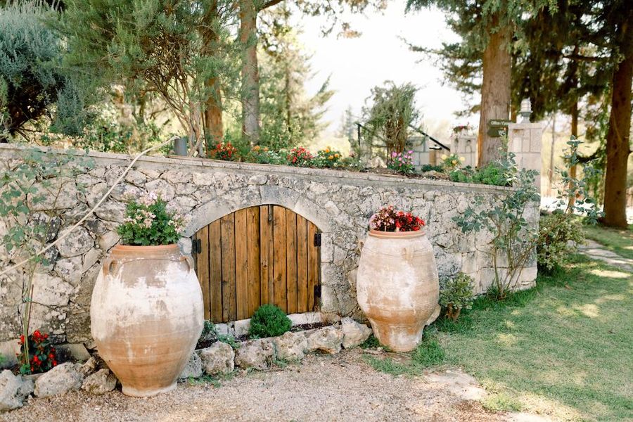 a double wood door of stone low building with two flower pots on the both sides at Dourakis Winery outside