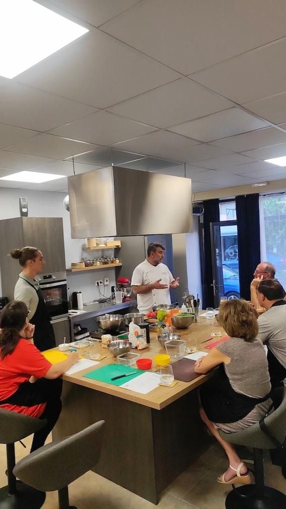 a group of people listening a chef giving a cooking lesson, around the table, at Savor Nafplio