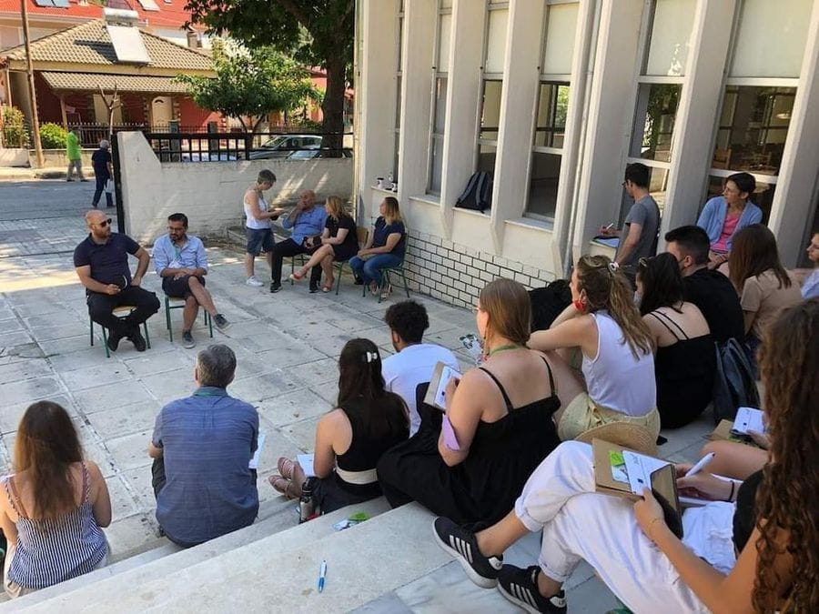 a group of tourists sitting in the amphithere and listening two men at Gralista Farm area