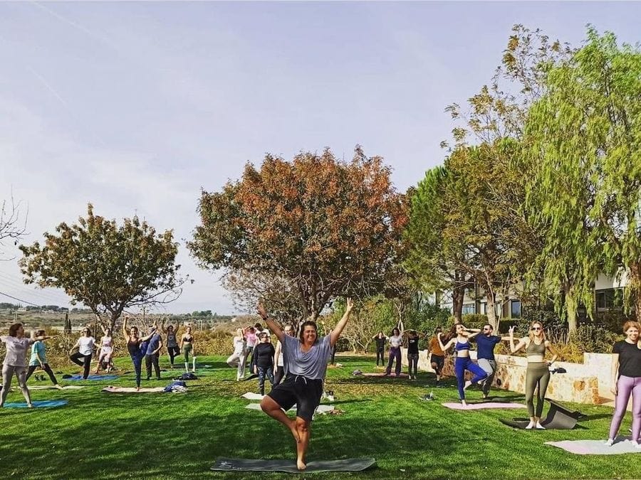 a group of women and men smiling and doing Pilates outside at Domaine Papagiannakos surrounded by trees