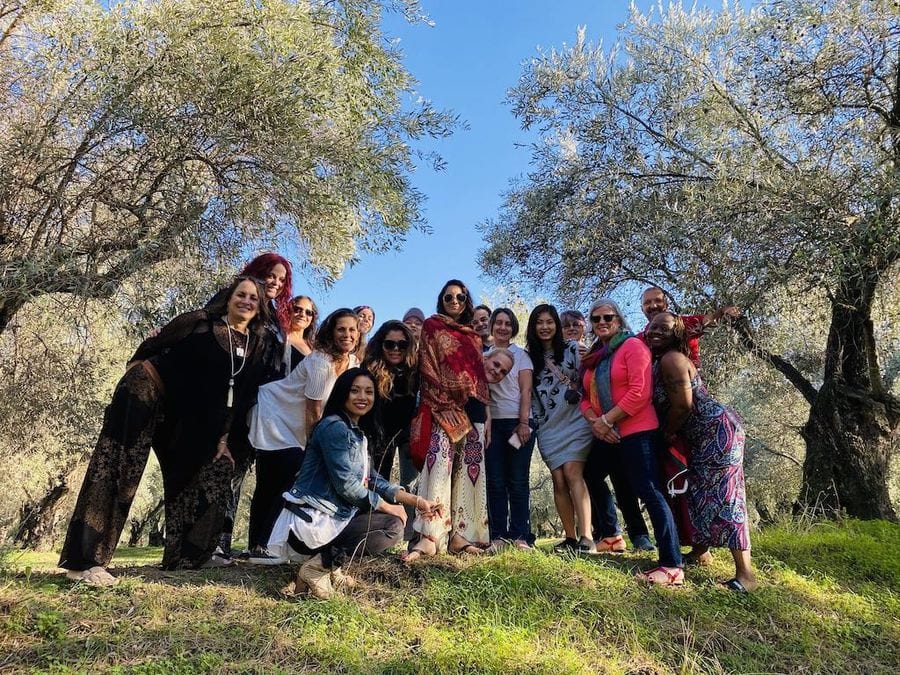 a group of women watching and smile happily at the camera at Socrates Olive Oil olive grove