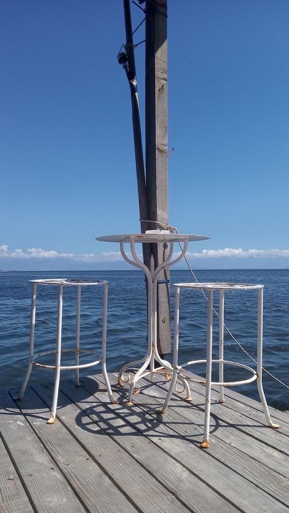 a table and two metal chairs on the deck of Stefanos Kaneletis’ fishing boat and the sea in the background
