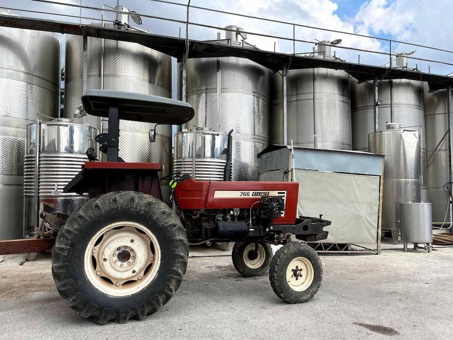 aluminum wine storage tanks and a tractor outside at at Papagiannis Winery premises