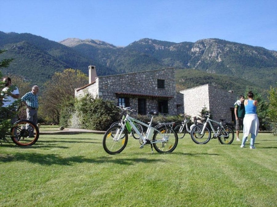 bicycles on the green lawn with tourists that waiting with Amfikaia stone buildings and mountains in the background