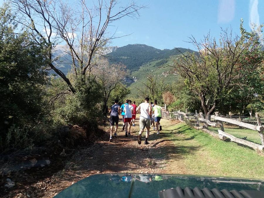 a group of men running on Amfikaia dirt road with trees on the both sides