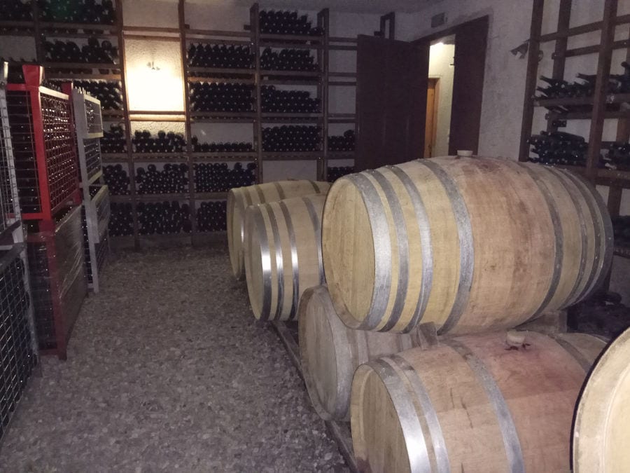 stacked bottles on top of each other and wine barrels at 'Argatia Winery' cellar