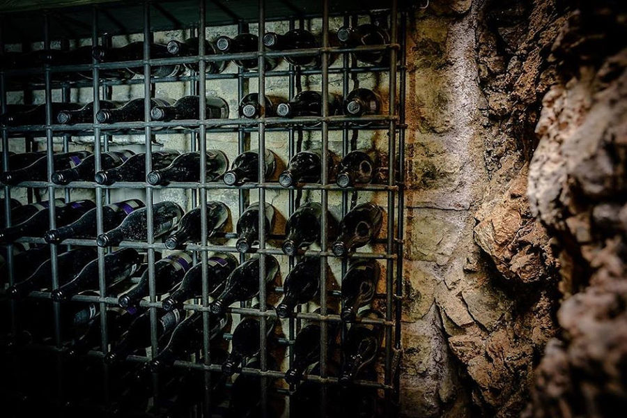 stacked bottles on top of each other in the storage frame on the stone wall at Argyriou Winery