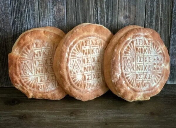 Three artos means engraved personalized round breads sating vertical on wood surface