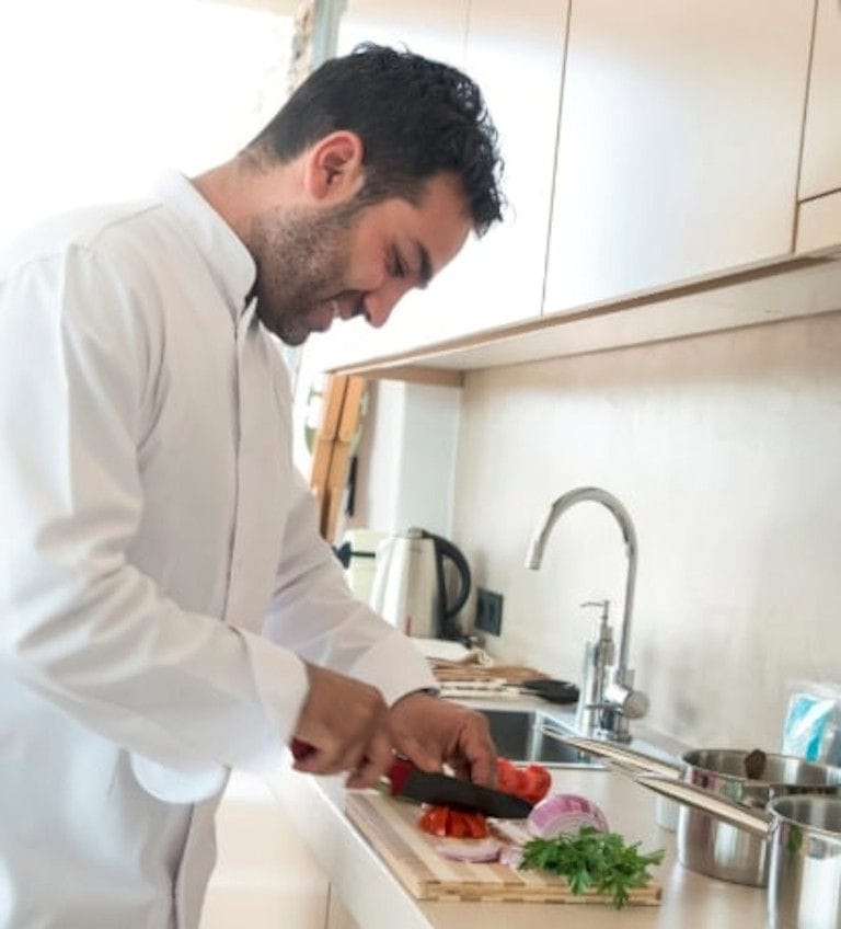 chef smiling and cooking and cutting tomatoes and vegetables in 'Astarti' kitchen