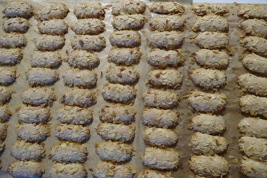 Close-up of rows of Greek ‘ergolavos’ are sweets crunchy on the outside, soft and chewy in the inside with shelled almonds on top on bakery pan