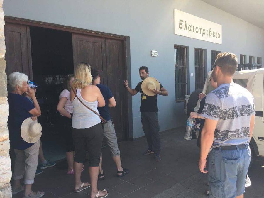 tourists in front at building's Ben Olive Mill, listening to the guide