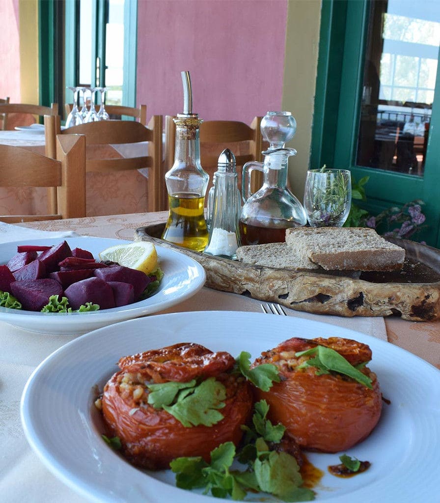 plates with food, bread, bottle with oil, bottle with wine on the table at Bioporos