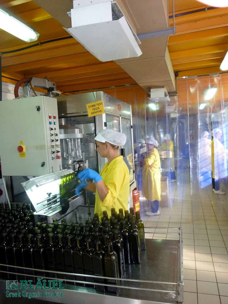 women placing bottles on the production machine at Bläuel Greek Organic Products