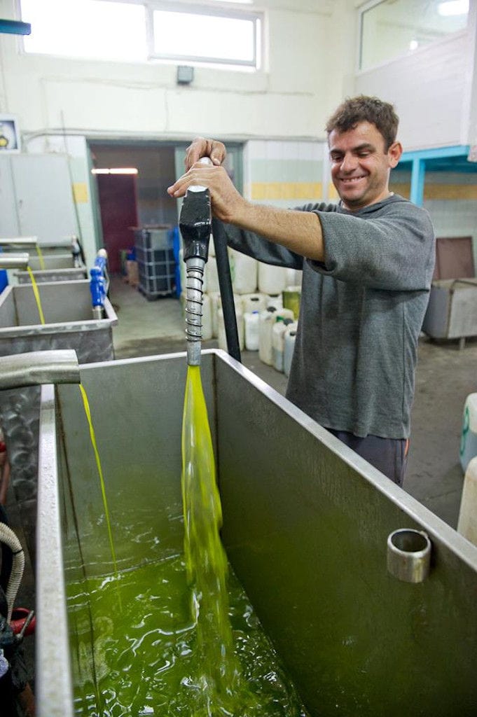 man puts oil in the container with a pump that he holds with his hands at Bläuel premises