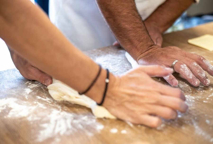 close-up of a woman and a chef kneading bread dough at Savor Nafplio