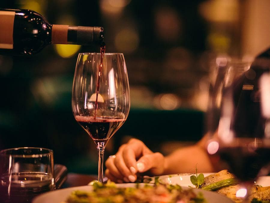 close-up of somebody that put wine in glass and somebody else waiting to taste it