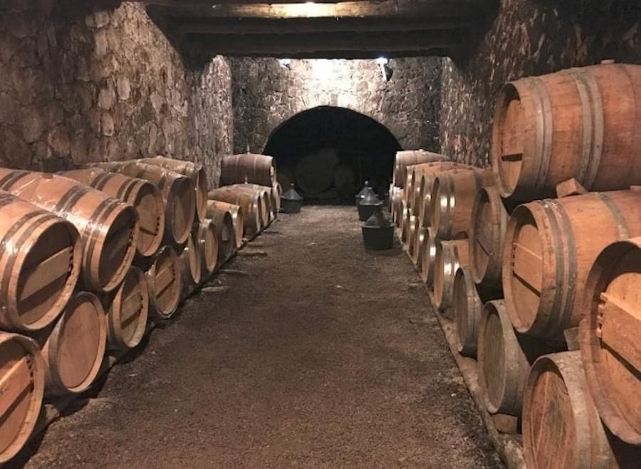 corridor at Dourakis Winery stone cellar with wine bottles on top of each other on the one side