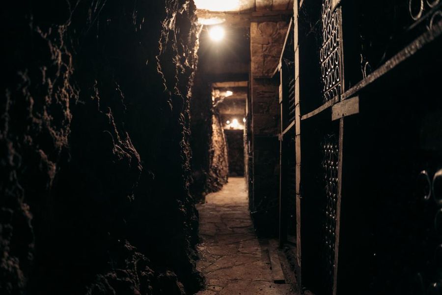 corridor at Dourakis Winery stone cellar with wine bottles on top of each other on the one side