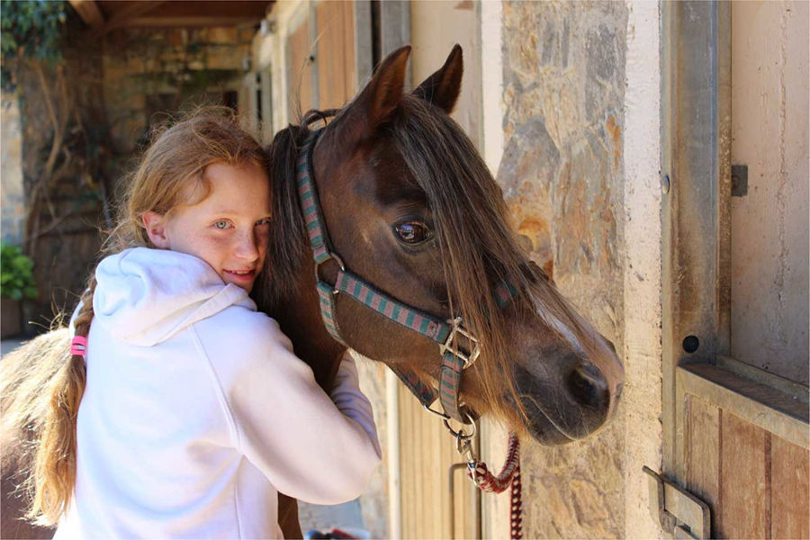 happy girl caressing brown horse at Country Hotel Velani