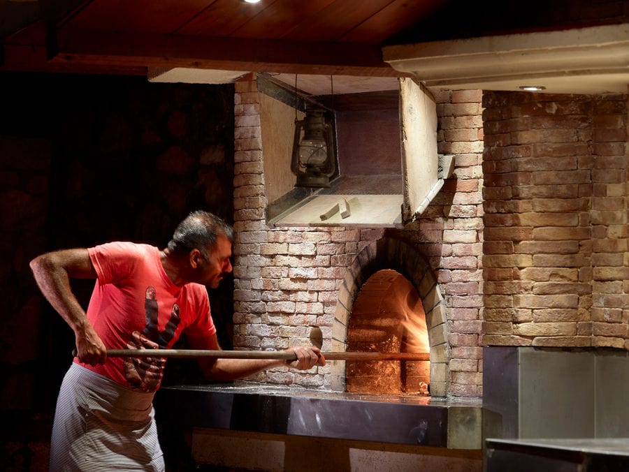 man bakeing bread in the oven at Country Hotel Velani