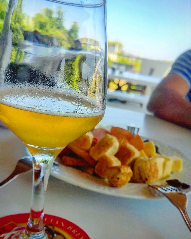 close-up of a glass with beer at Cretan Brewery restaurant and plate with fried cheeses in the background