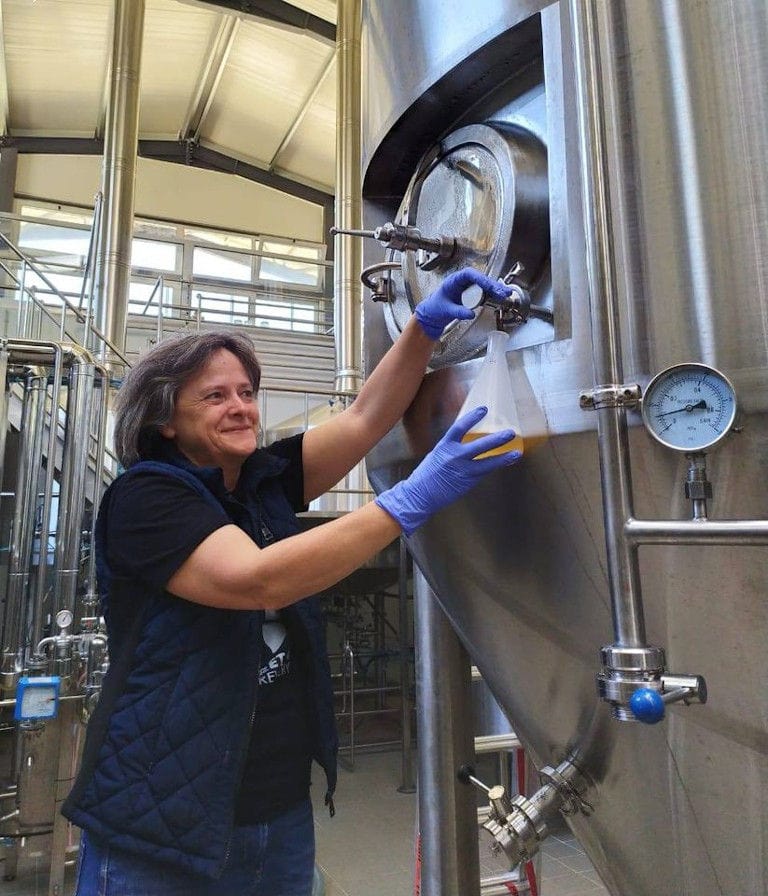 woman collecting beer sample from the tank at Cretan Brewery plant