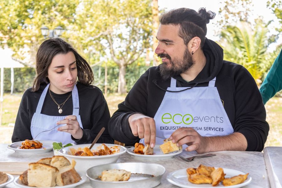 Two people joyfully indulge in Crete's traditional foods they lovingly prepared themselves, their faces reflecting satisfaction and delight as they savor the flavors of authentic Cretan cuisine, fostering a deep connection to the island's rich culinary heritage.