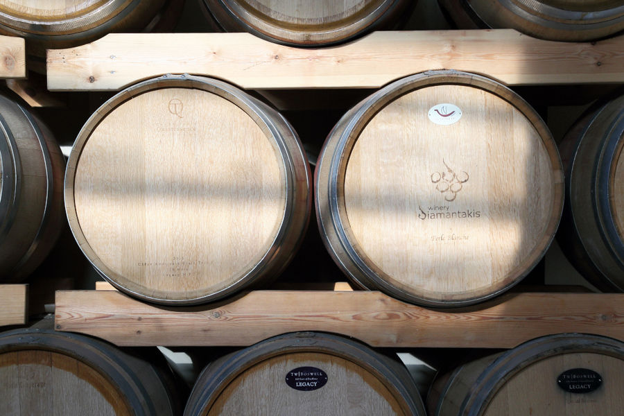wine barrels on top of each other in a row on the wood panelsat 'Diamantakis Winery' cellar
