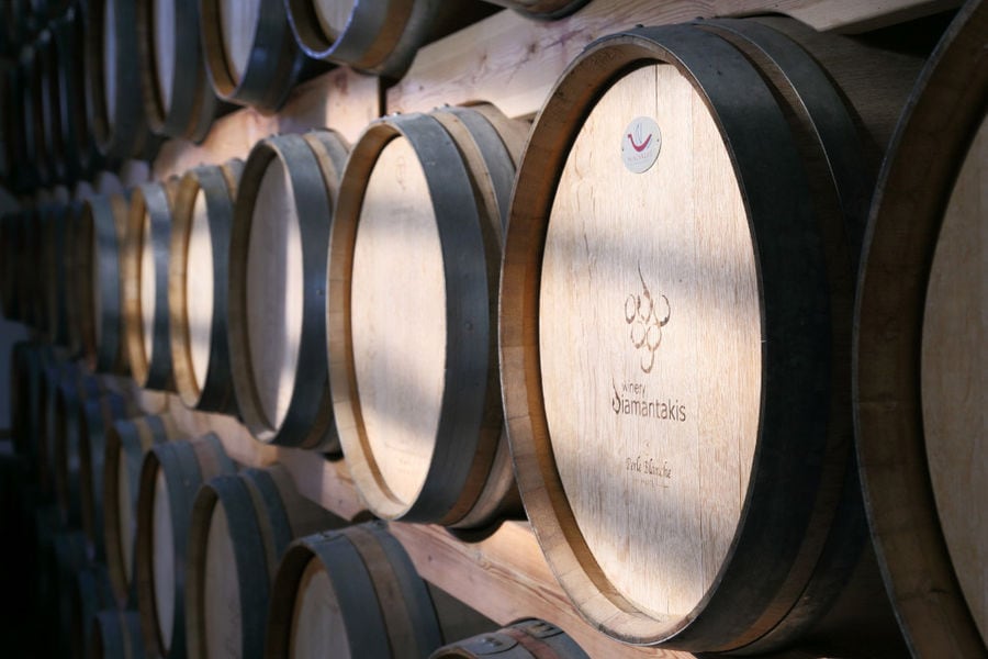wine barrels on top of each other in a row on the wood panelsat 'Diamantakis Winery' cellar
